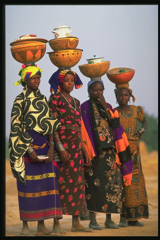 Vajzat me kostume ngjyra me pjata qeramike mbi kokën e tij