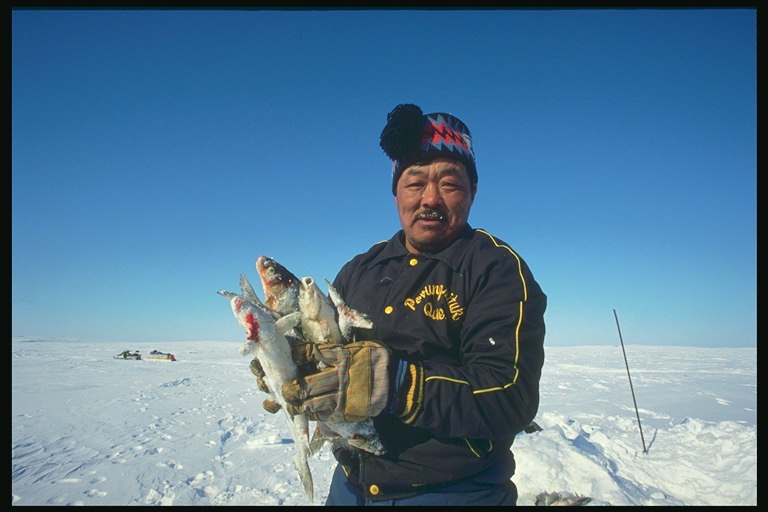 Zima. Muž s čerstvými rybami v ruke