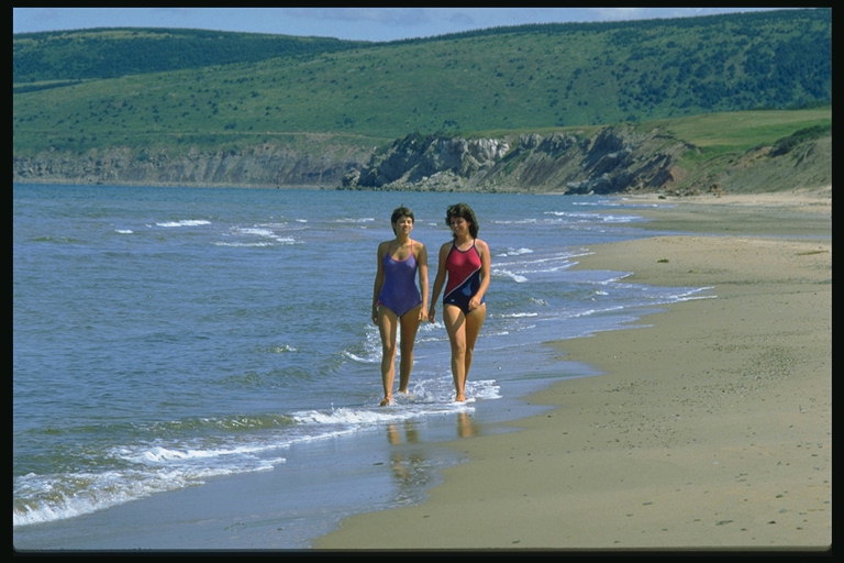 Пешеходна момичета в бански костюми на плажа