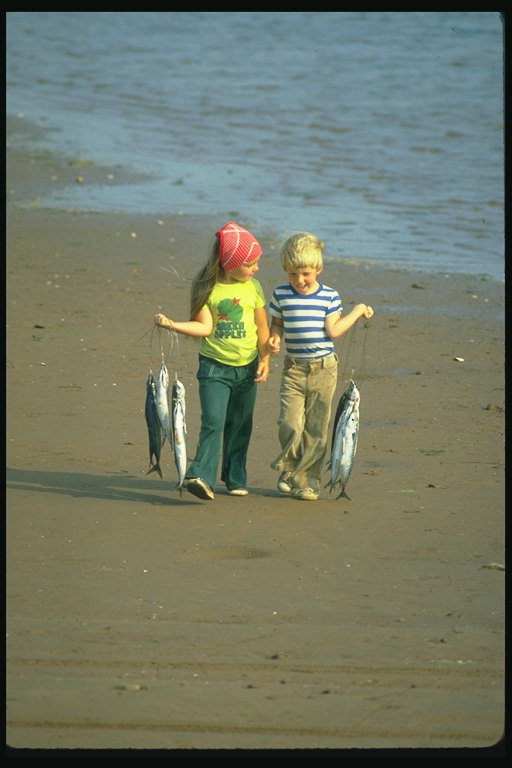 Los niños con un pez en sus manos en la playa