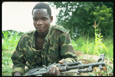 El hombre joven en uniforme de faena, con ametralladora en las manos de