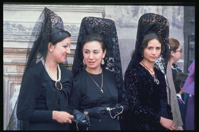 Women in black dresses. Black lace veil