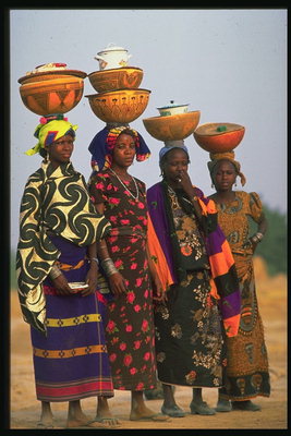 A lányok színes jelmezekben kerámia edényeket a fején