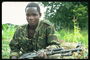 De jongeman in militaire fatigues met een machine-geweer in de handen van