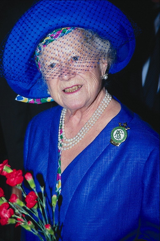 Женщина в синем костюме в шляпке и с цветами