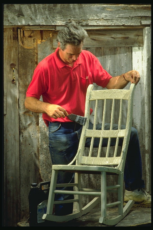 A človek maľuje stoličky