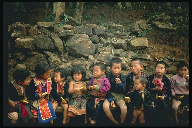 Kinderen op een bankje in de buurt van een stenen muur
