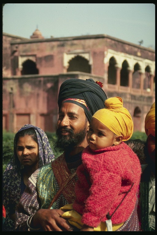 A man in a black turban with a girl at the hands