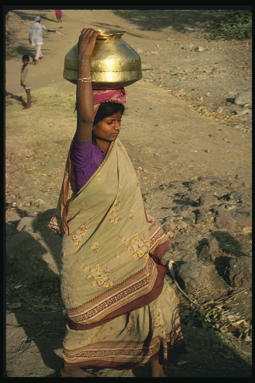 Một phụ nữ với một pitcher kim loại trên đầu của cô