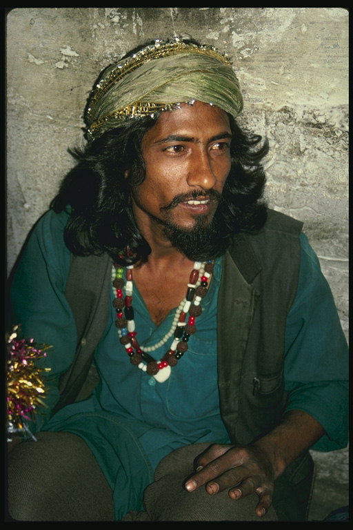 Un homme dans une chemise vert foncé, d\'un turban avec un fil brillant, avec des pierres et des perles colorées