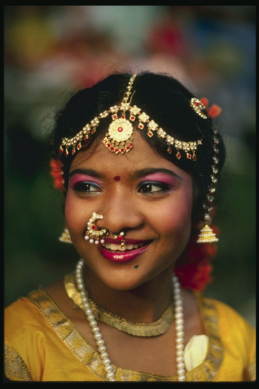 Une jeune fille, le maquillage lumineux, des bijoux en métal et des pierres