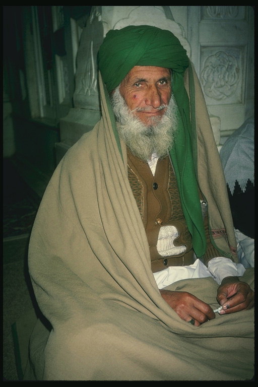 Un home en unha luz verde manto marrón e turbante