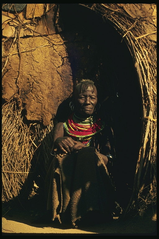 Una mujer en una choza de barro y hierba seca