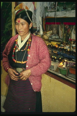 A woman in a striped skirt and multicolored beads. A red dot on forehead