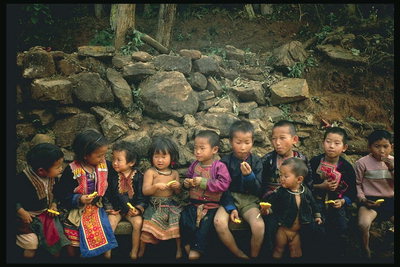 Trẻ em trên một băng ghế gần một bức tường đá