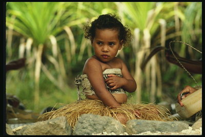 Afrika. Dívka v sukni s rostlinami. Kudrnaté vlasy dítě
