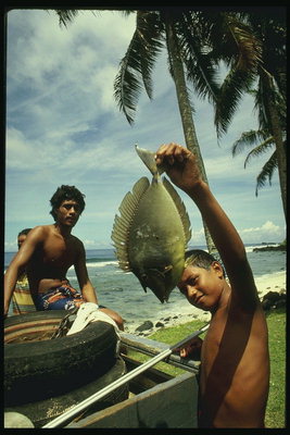 الصبي مع سمكة في يديه