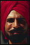 A man in a dark red turban. Black short beard
