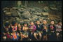 Fëmijët në një stol pranë një mur guri