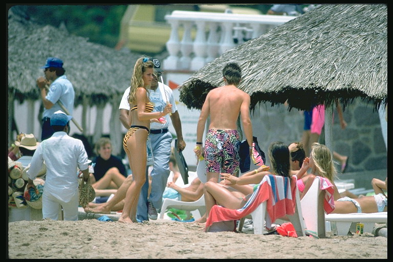 Компания людей на пляже возле зонтика с травы