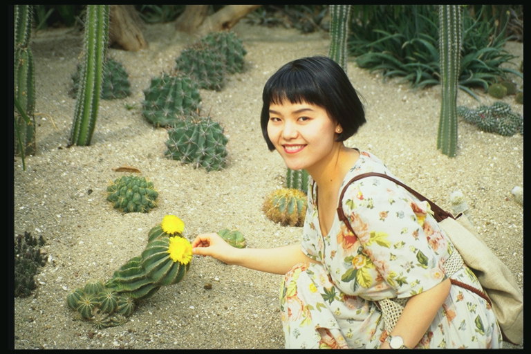 Девушка с короткими темными волосами на фоне цветущего кактуса