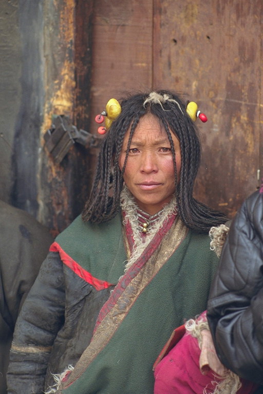 Женщина с косичками и вплетенными предметами в волосах