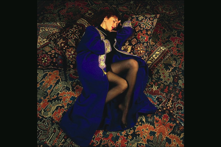 Девушка в темно-фиолетовой накидке среди подушек с восточными орнаментами