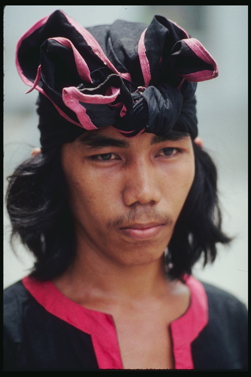 Il giovane uomo in un foulard nero con bordi rosa