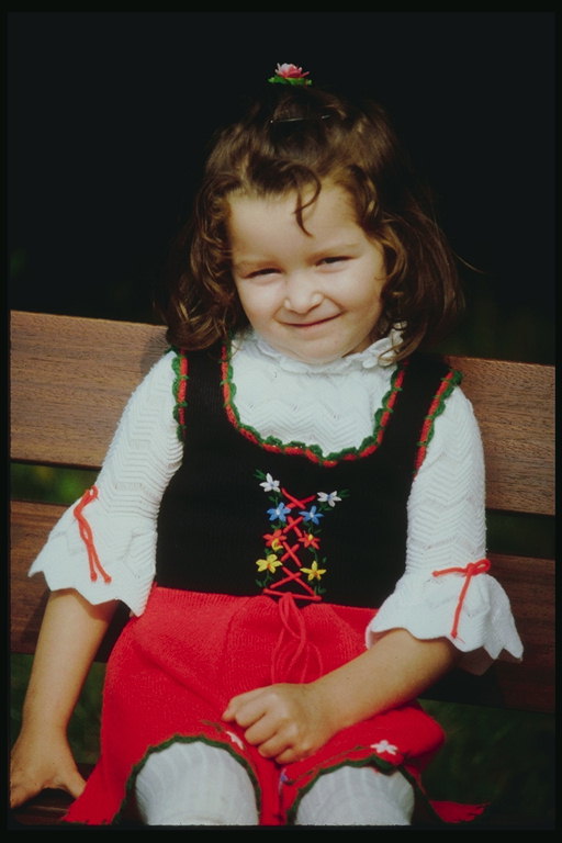 Девочка в красной юбке и темной жилетке с вышитыми цветами