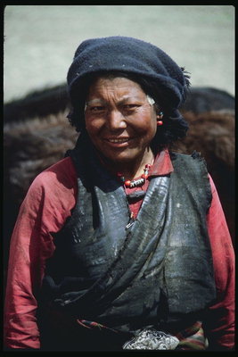 Μια γυναίκα σε ένα μαντήλι και σκούρο δέρμα γιλέκα