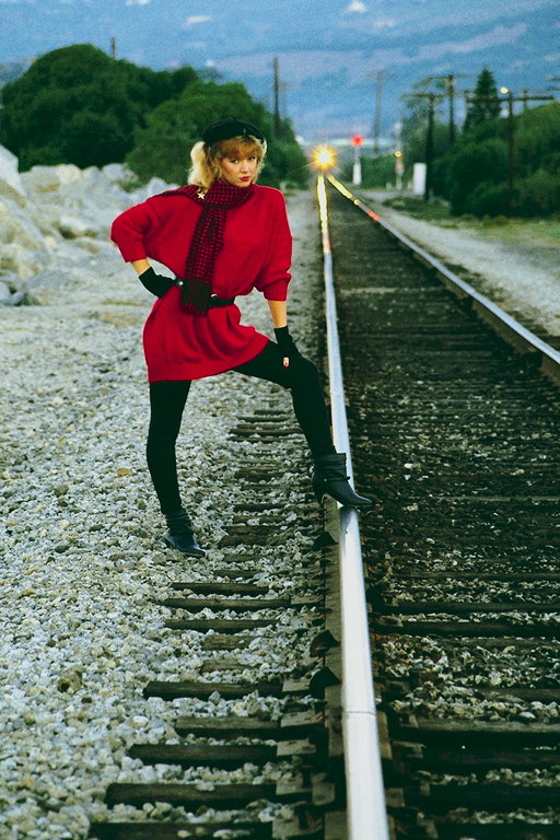 Девушка в длинном расном вязаном платье. Рельсы железной дороги