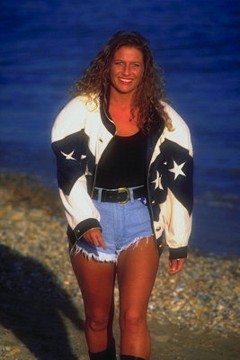 Девушка в коротких джинсовых шортах и черно-белой куртке со звездами. Волнистые волосы