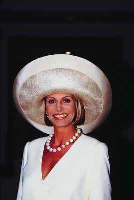 Женщина в белой шляпе с большими полями и бусами на шее