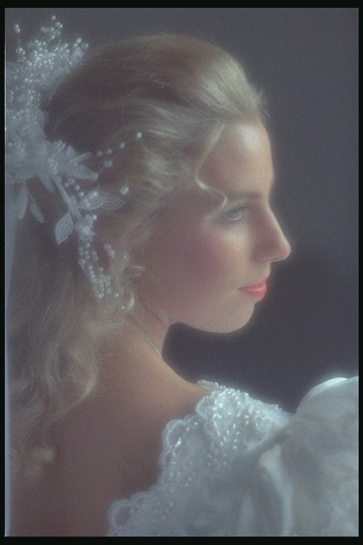Невеста в белом платье с цветами в волосах и румянцем на щеках
