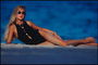 Девушка в черном купальнике на белом песке