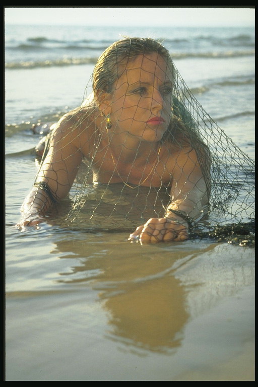 Девушка на берегу под сеткой рыбака