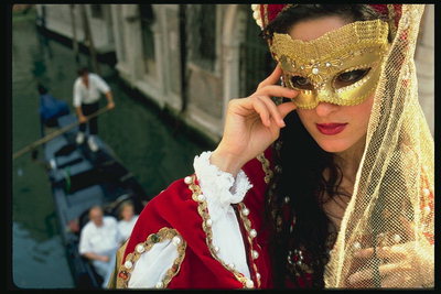 Девушка в карнавальном костюме с красного бархате и золотой маске