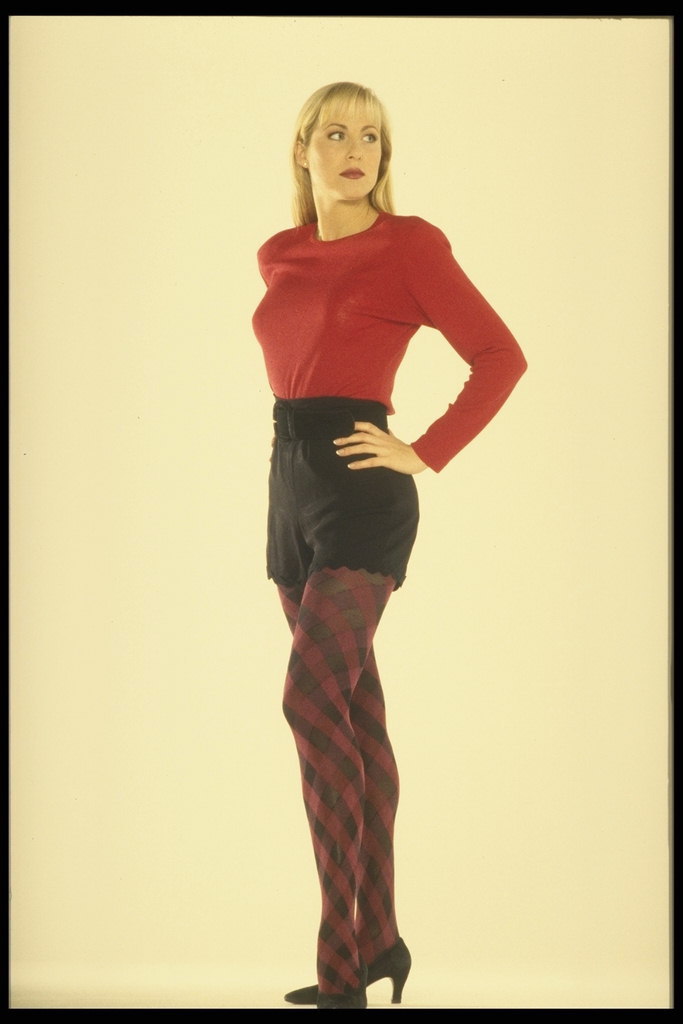 Девушка в красном свитере и в черных шортах