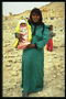 Женщина с младенцем на руках на фоне руин города