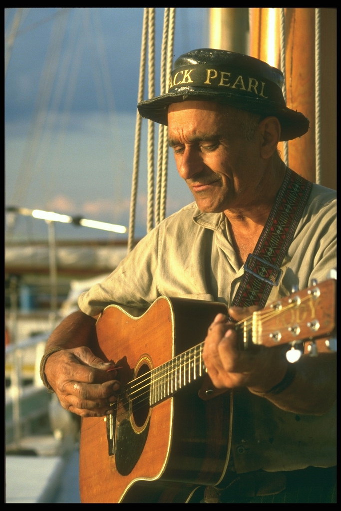 Фотография старого лоцмана играющего на гитаре и поющего весёлую песню