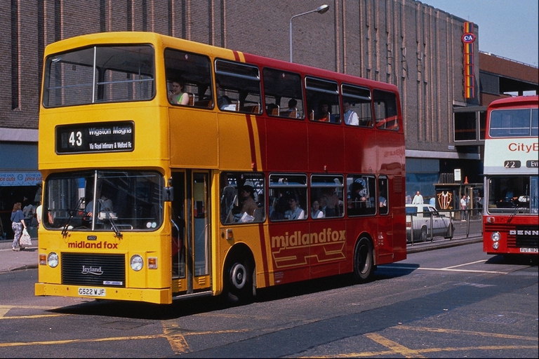 En gul dubbeldäckad buss vid hållplatsen. Busstationen centrum för affärsverksamhet i staden