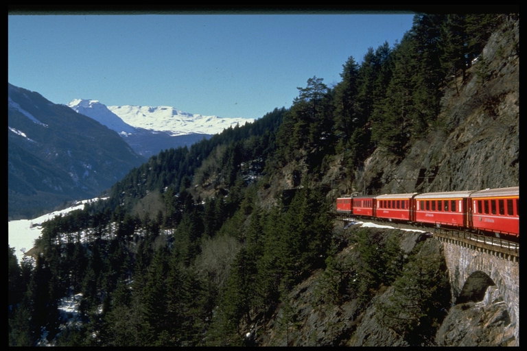 Среди заснеженных горных вершин Швейцарии путь поезда проходит по краю опасных обрывов