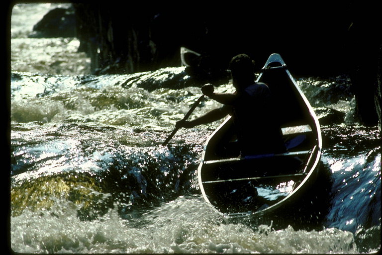 Sportists - extremals ar koka laivu Ložņu caur akmeņainas krāces un kalnu upes