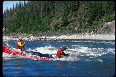 Vogatori nella loro kayak remi contro la corrente di un fiume di montagna