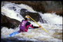 Dalam kayak biru dan kuning dan dayung, atlet turun sungai