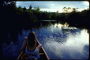 Девушка в шортах на реке в вечернее время, плывущая на каноэ
