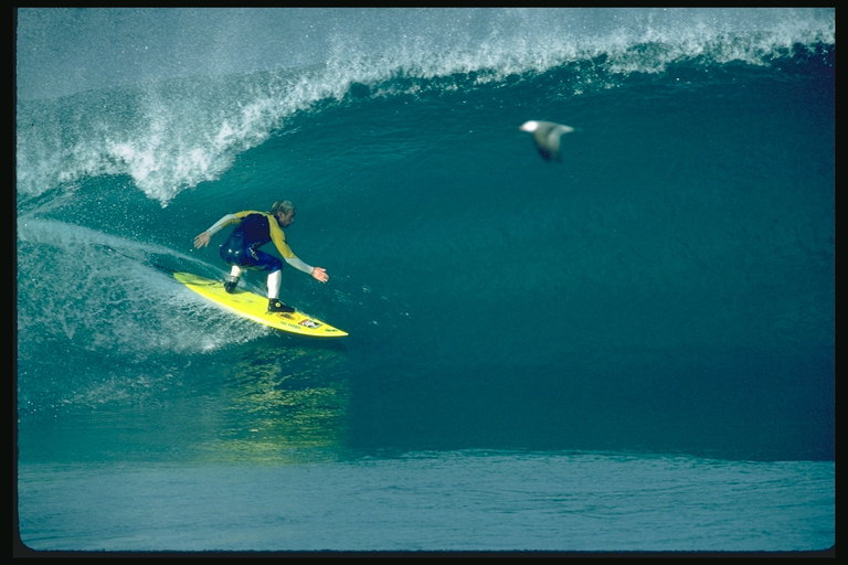 На жёлтом серфингборде по волнам средиземного моря балансирует спортсмен