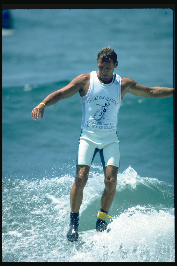 Surfer κοντά στο συμβούλιο αποδεικνύει τέχνη του αθλητικού