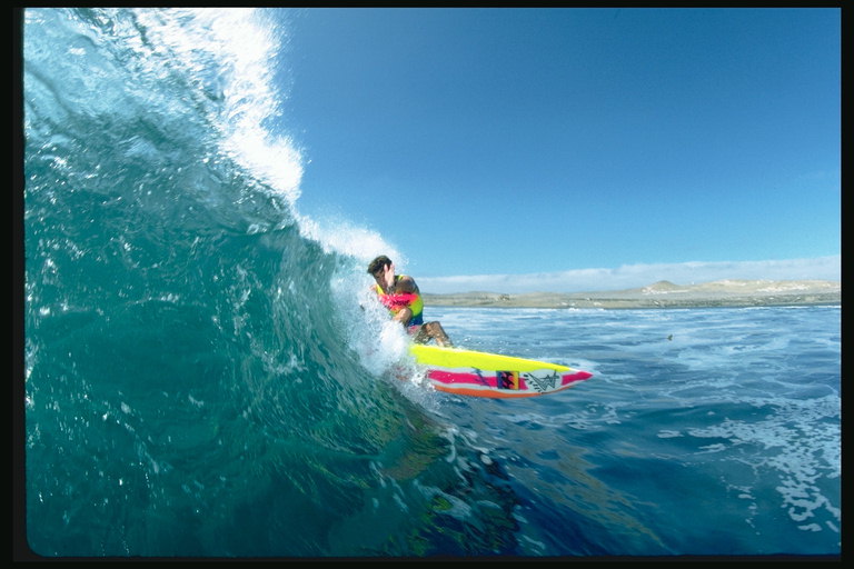 En stor mur af vand fejer sin måde surfer
