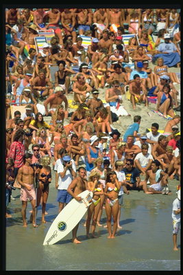 Os espectadores na praia, em antecipação das corridas espectaculares sobre surfe